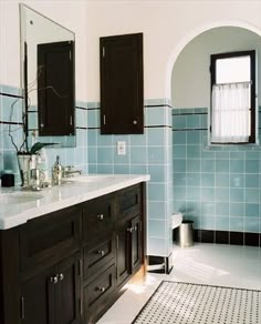 a bathroom with blue and white tiles on the walls, two sinks, and mirrors