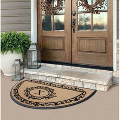 a door mat with the letter k on it and a potted plant next to it