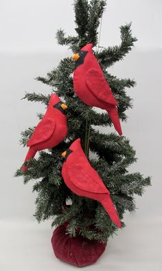 three red birds sitting on top of a christmas tree