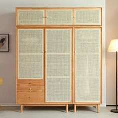 a room with a large wooden cabinet next to a lamp