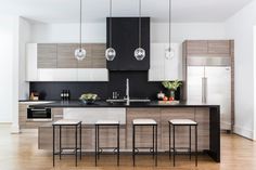 a modern kitchen with black and white cabinets, wood flooring and bar stools