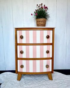 a pink and white striped dresser with flowers on top