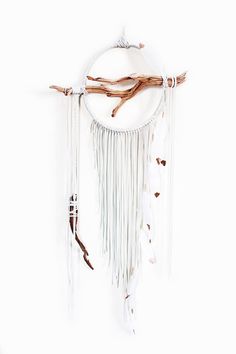 a white dream catcher hanging on a wall next to a tree branch and other items