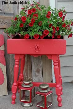 a red potted planter with flowers in it sitting on top of a table