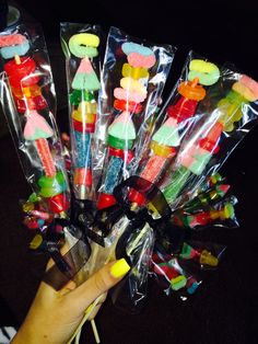 there are many candy sticks wrapped in plastic wrappers and being held by someone's hand