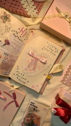 an open book with pink ribbon and bows on it next to other cards, gifts and decorations