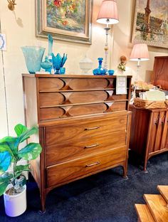 a wooden dresser sitting next to a lamp on top of a blue carpeted floor