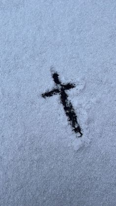 a cross is shown in the snow with it's shadow coming out from behind