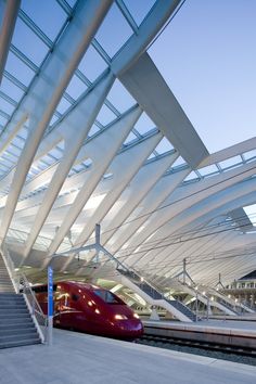 a red train traveling down tracks next to a loading platform