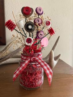 a jar filled with buttons sitting on top of a wooden table next to a pair of scissors