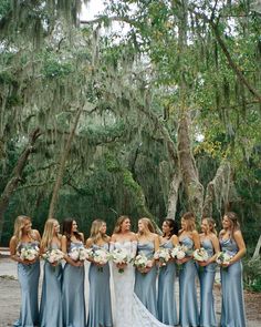 a group of women standing next to each other in front of trees with moss growing on them