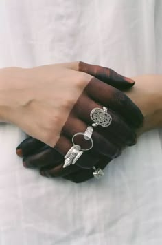 a woman's hands with rings on them, both holding onto each other while wearing black gloves