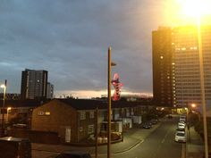 the sun shines brightly on an urban street at dusk, with tall buildings in the background