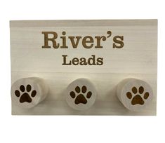 a wooden sign with three paw prints and the words river's leads