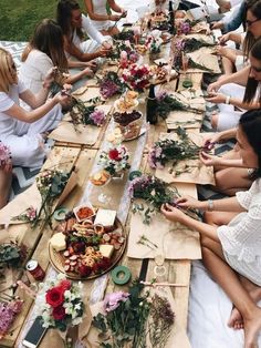 a group of women sitting at a long table with plates and bowls of food on it