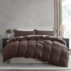 a bed with brown sheets and pillows in a room