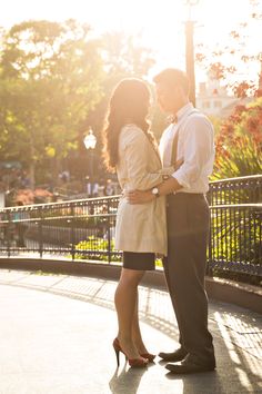 a man and woman standing next to each other in front of a street light with the sun shining on them