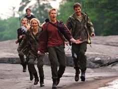 a group of people walking down a street next to each other with trees in the background