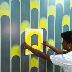 a man is painting a wall with yellow letters