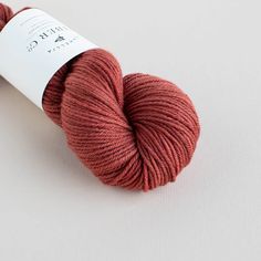 a skein of red yarn sitting on top of a white surface with a tag