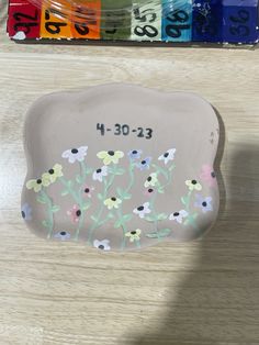 a white plate with flowers painted on it and some markers next to the trays