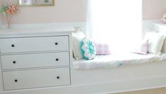 a white dresser and window seat in a child's room