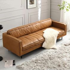 a brown leather couch sitting on top of a white rug