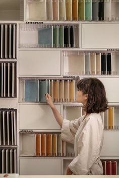 a woman is standing in front of a book shelf with many colors of books on it