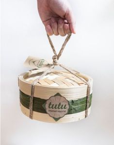 a hand holding a bamboo basket with twine tied around the handle and tag that says tutu on it