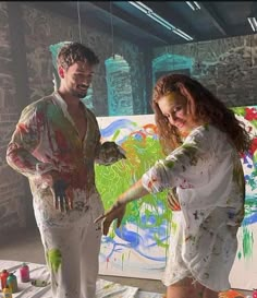 two people standing in front of an easel with paint on it