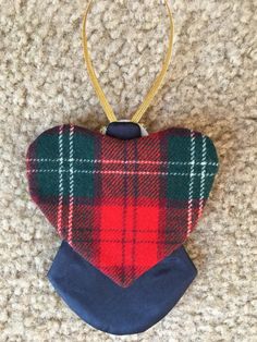 a red, green and blue plaid heart shaped ornament hanging from a gold metal hook