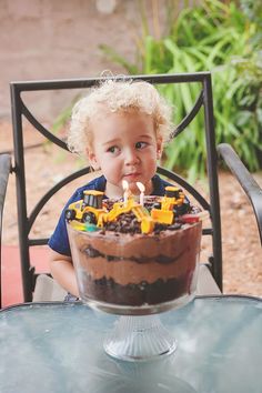 a little boy sitting in front of a birthday cake