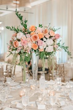 a vase filled with lots of flowers on top of a white table cloth covered table