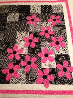 a black and white quilt with pink flowers on it