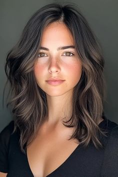 Woman with wavy, shoulder-length brown hair, wearing a black top, looking directly at the camera. Natural Cool Brunette, Brookie Hair Color, Dark Brunette With Cool Tone Highlights, Best Hair Color For Summer Skin Tone, Brown Hair After Blonde, Ashy Brown Hair Olive Skin, Brunette Hair Color Winter, Natural Looking Brown Hair Highlights, Brunette Hair Color Fall 2024