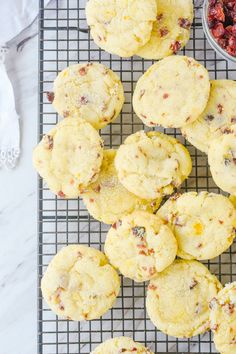 cranberry orange cookies on a cooling rack next to a bowl of dried cranberries