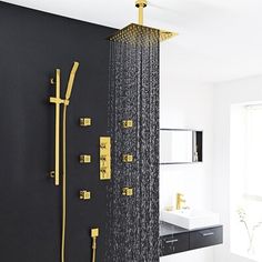 a shower head with thermostaer and handset in gold on a black wall