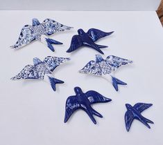 six blue and white ceramic birds sitting on top of a sheet of paper next to each other