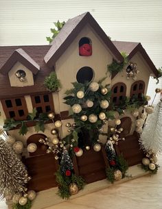 a birdhouse decorated with christmas decorations and greenery