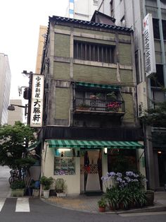 an old building with green awnings and flower boxes on the side of it