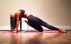 a woman is doing yoga on a mat with a hoop around her neck and hands behind her head