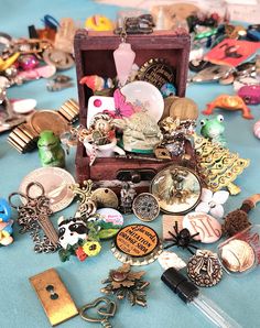 there are many different items in the box on the blue tablecloth, including brooches and key chains