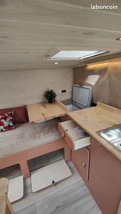 the interior of a tiny house with wood flooring and pink walls, white counter tops and cabinets