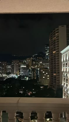 the city is lit up at night from the balcony