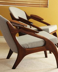 two chairs sitting next to each other on top of a carpeted floor in front of a window