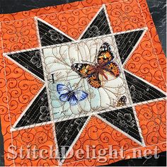 an orange and black quilted star with butterflies on it's center, sitting on top of a table