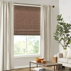 a living room with a couch, coffee table and window covered in bamboo roman shades