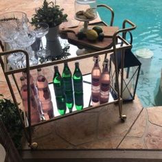 a table with bottles and glasses next to a swimming pool