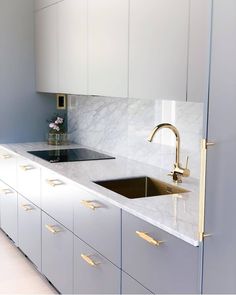 a kitchen with marble counter tops and gold faucets on the sink, along with white cabinets