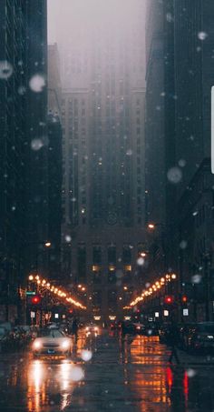 a city street at night in the rain with cars driving down it and buildings on both sides